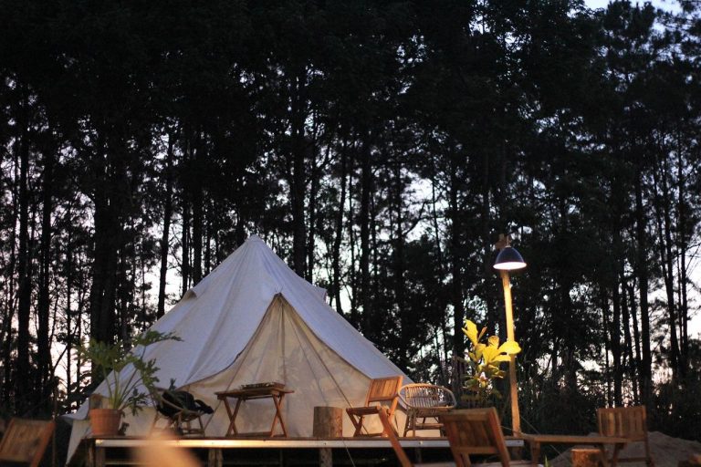 Glamping safaritent met comfortabele inrichting, bed en zithoek omgeven door natuurlijk landschap
